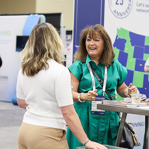 two woman standing and networking at a conference