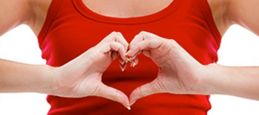 A woman in a red tank top makes a heart with her hands. Her finger form the upper curve of the heart and her thumbs form the bottom point.