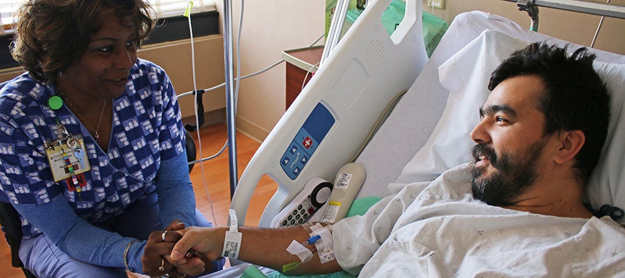 AHA Patient Safety Initiative Priorities. A nurse at a patient's beside holds the patients hand while speaking with the patient.