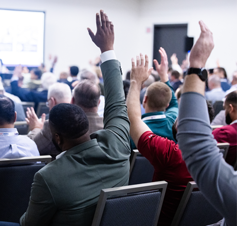 Attendees raise their hands in a PDC Summit session room
